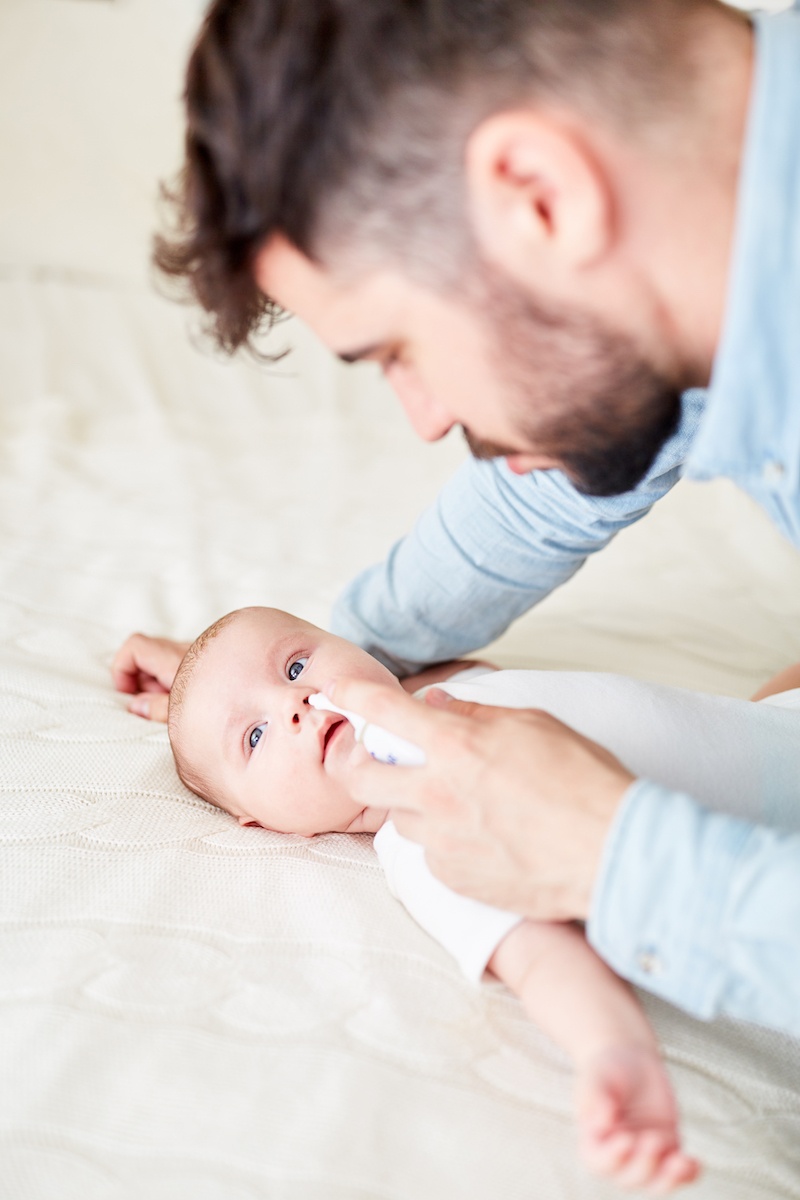 Dad using nasal bulb for sick baby