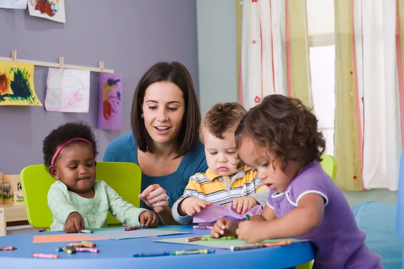 Toddlers playing with teacher at day care