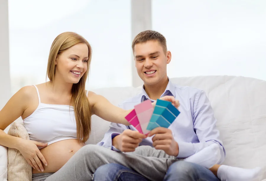pregnant couple looking at paint swatches to predict baby's gender