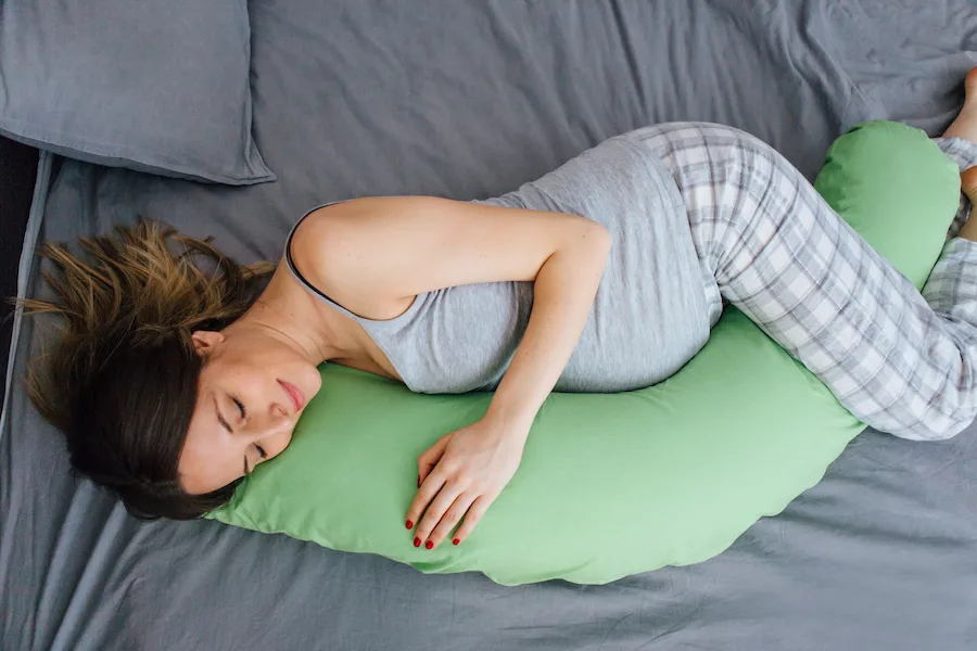 pregnant woman using pregnancy pillow for sleep - pregnancy hacks
