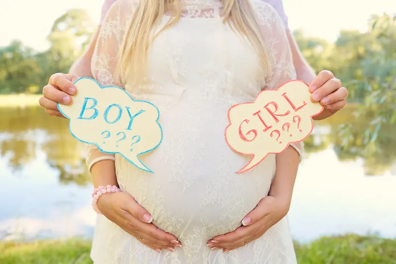 parents predicting baby's gender holding boy or girl sgns