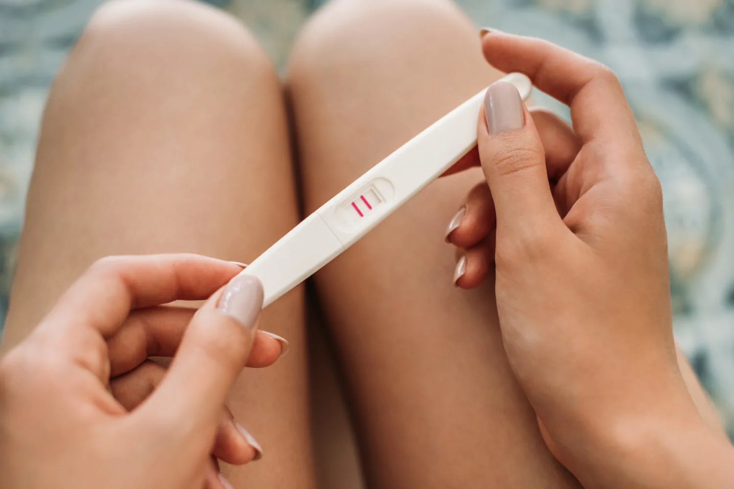 woman holding positive pregnancy test - 15 things to do when you find out you're pregnant