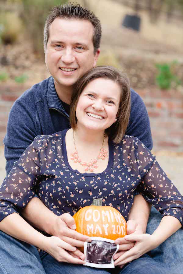 couple announcing pregnancy with a pumpkin pregnancy announcement