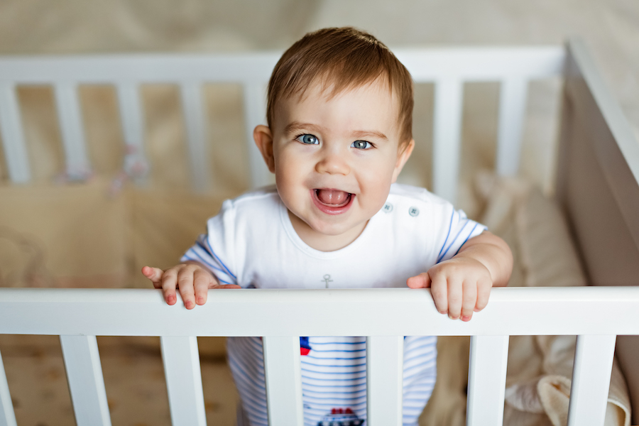 baby standing in crib happily