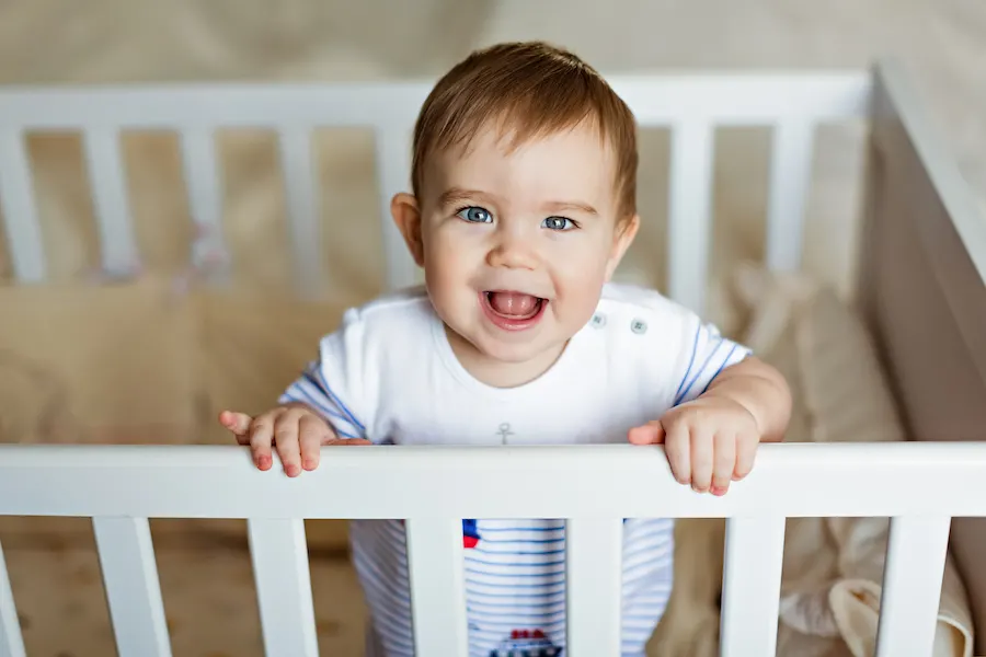 baby standing in crib happily