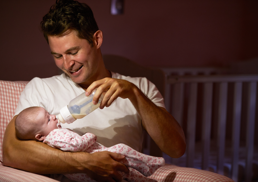 wean night feedings - dad happily bottle feeding baby at night in dark room