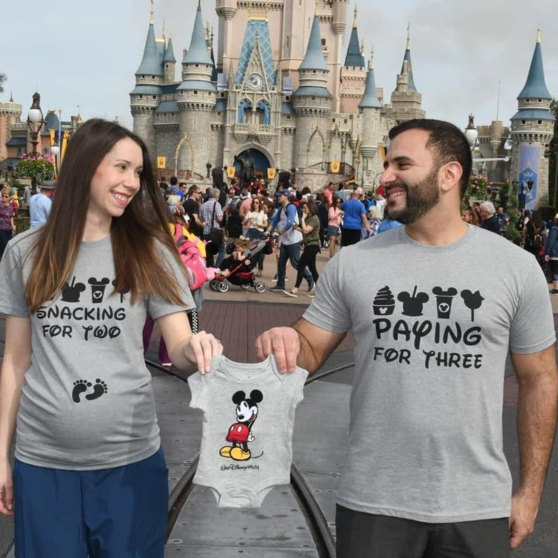 Disney pregnancy announcement - couple holding Mickey Mouse onesie at Disney