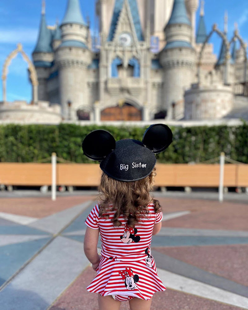 little girl wearing a Big Sister hat at Disneyland to announce pregnancy