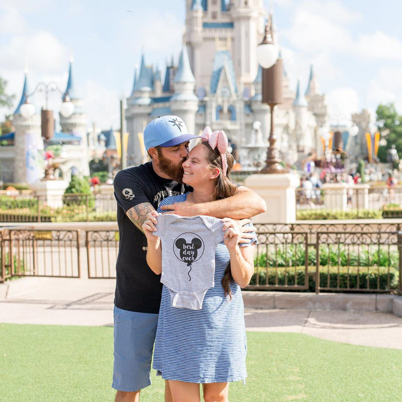 couple announcing their pregnancy in front of Disneyland castle