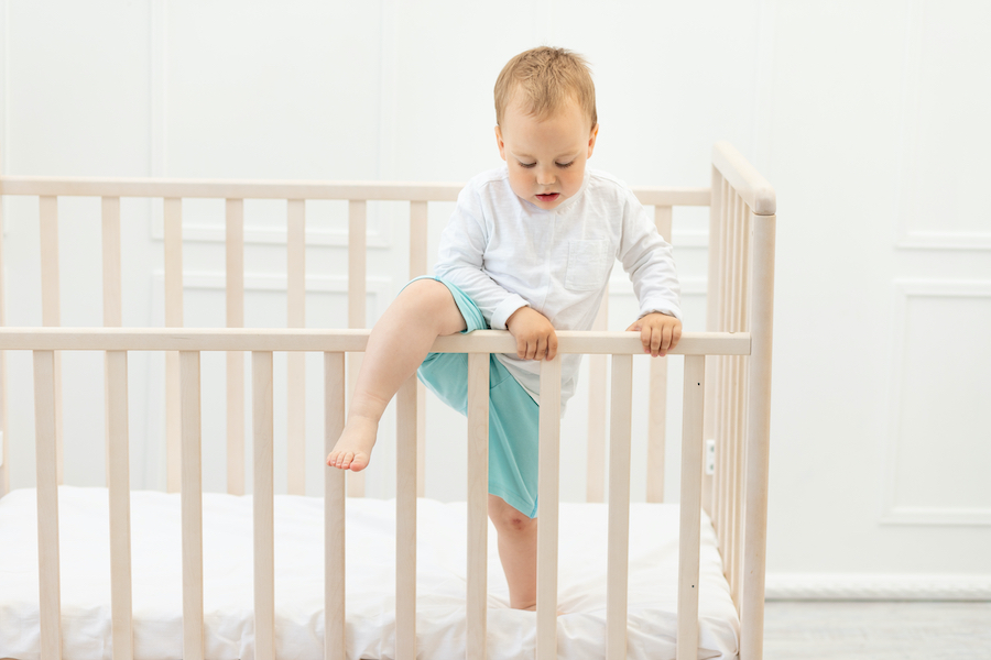 toddler boy climbing out of his crib