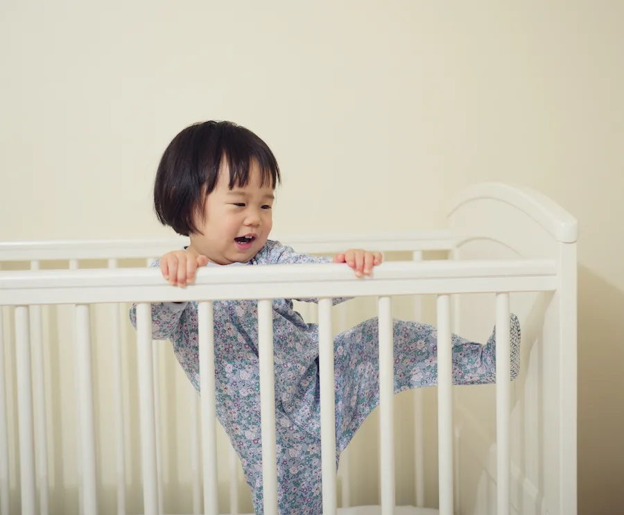 young toddler girl trying to climb out of crib