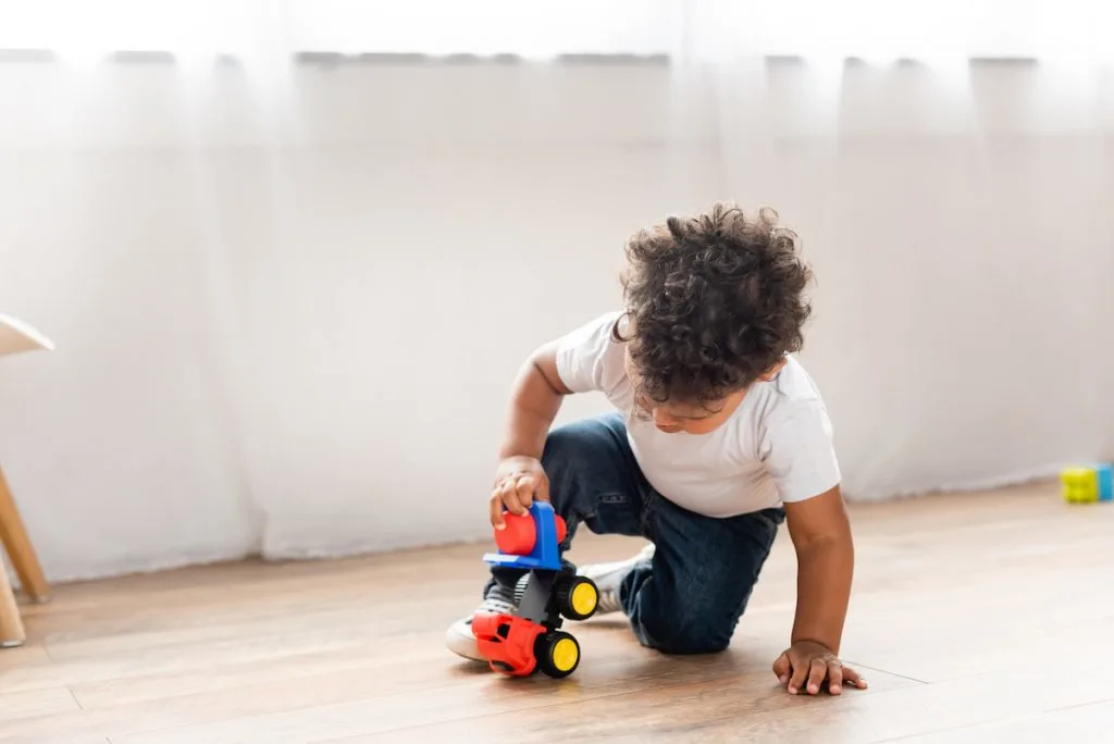 toddler playing independently with a car
