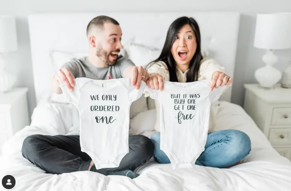 parents holding up onesies to announce twin pregnancy