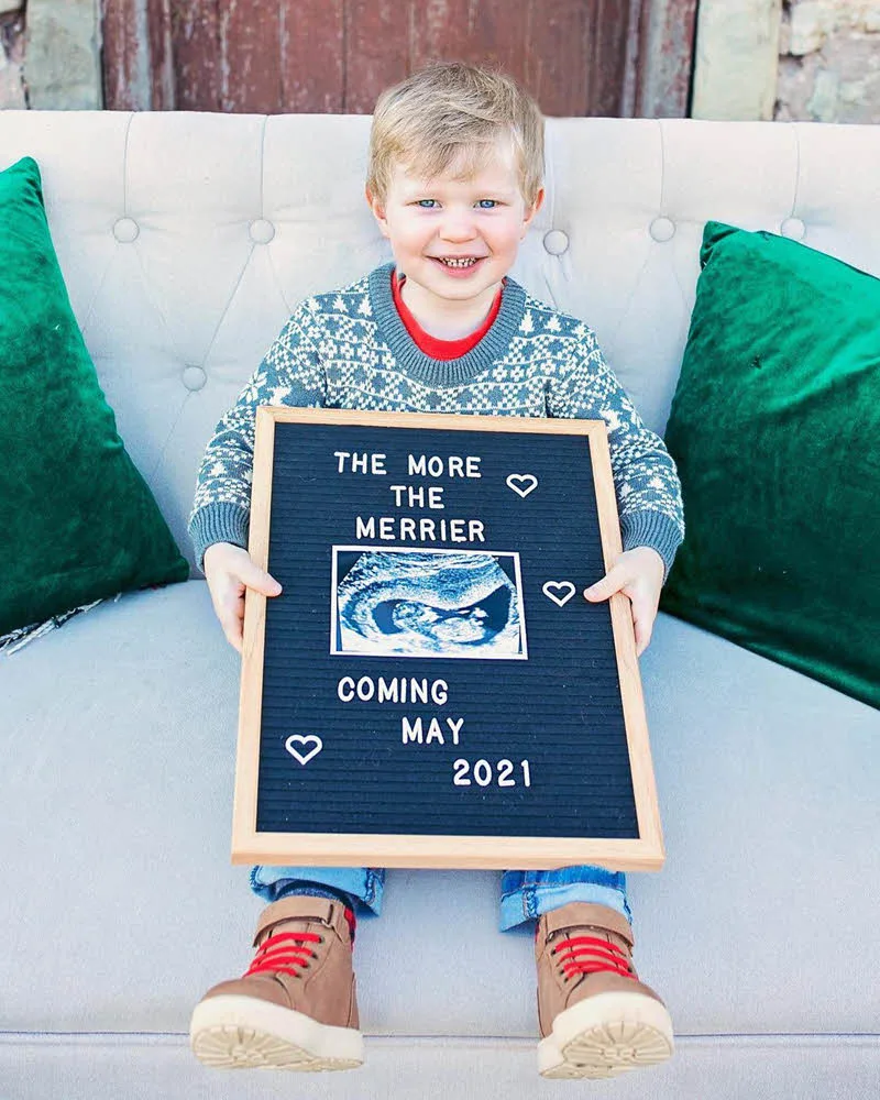 boy sitting on couch to announce new baby in family