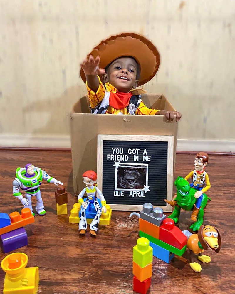 little boy dressed as Woody from Toy Story announcing new baby