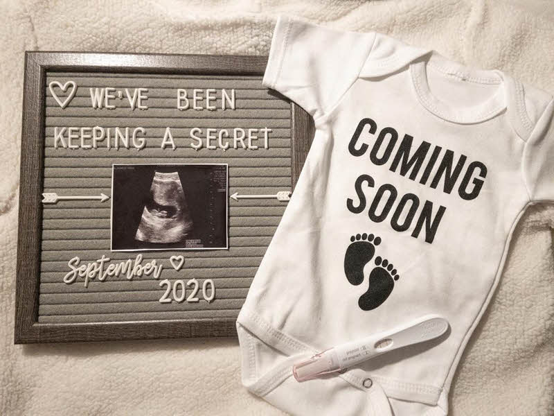 letter board pregnancy announcement with onesie and positive pregnancy test