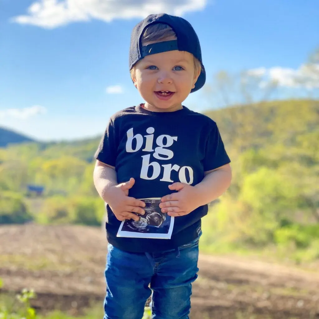 baby boy holding ultrasound photo to announce he's a big bro