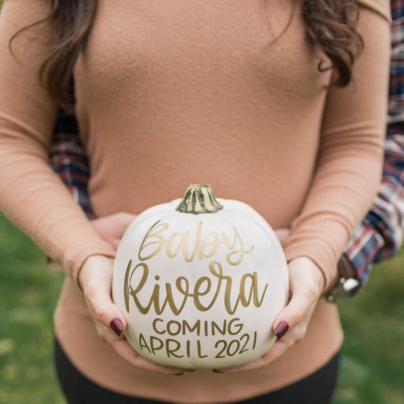 mom to be holding pumpkin to announce pregnancy