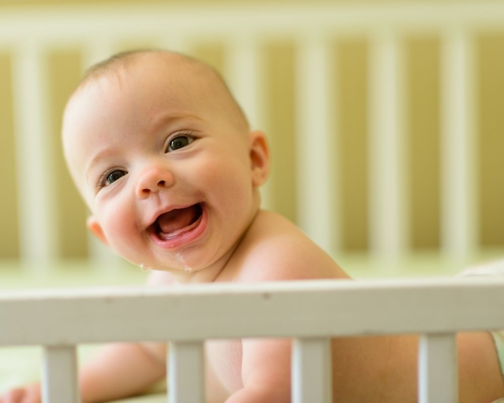 happy baby laying down smiling in crib