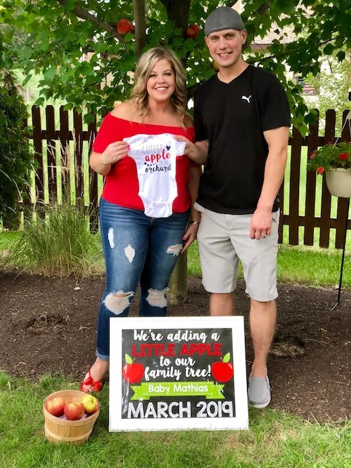 couple announcing pregnancy with apples