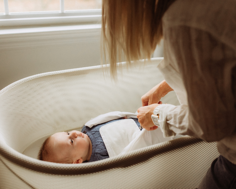 mom swaddling baby in SNOO bassinet