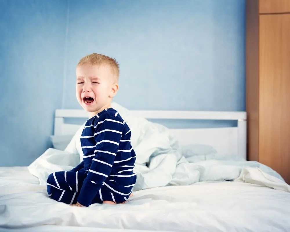 two year old in bed crying, resisting sleep
