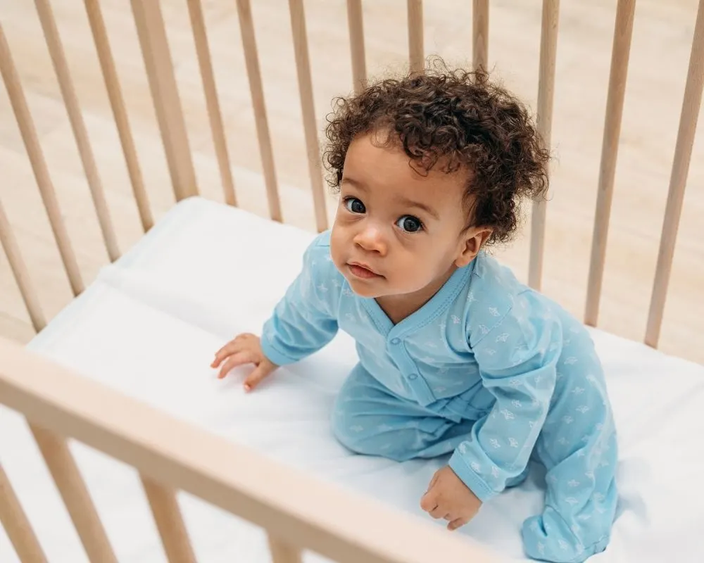 baby sitting on crib sheets