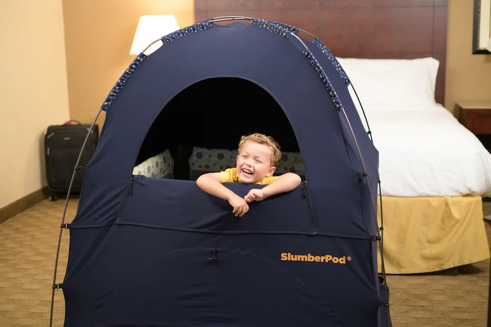 child in smiling in a slumberpod in a hotel room
