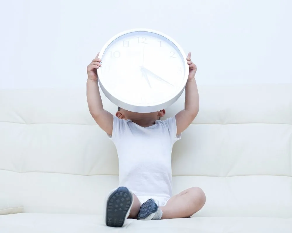 toddler holding clock up to show time