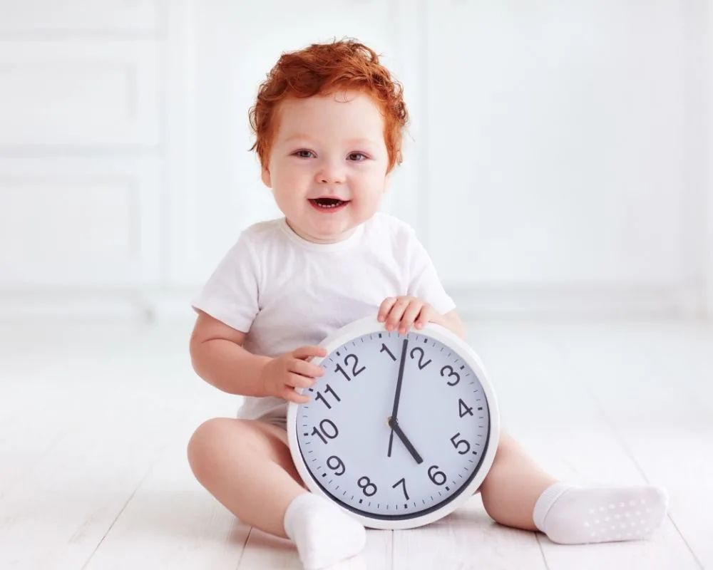 toddler sitting holding clock