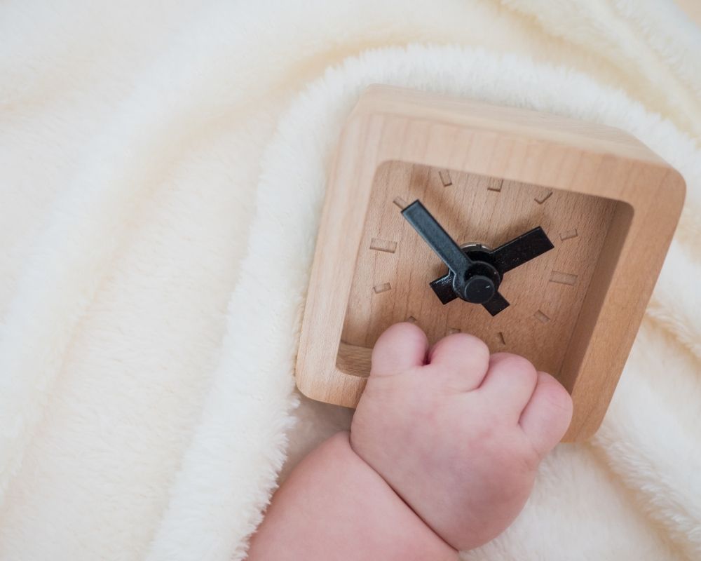 baby's hand holding clock