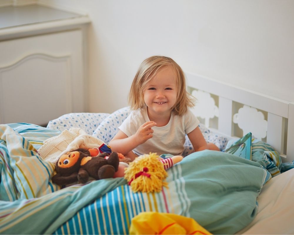 little girl awake smiling in bed