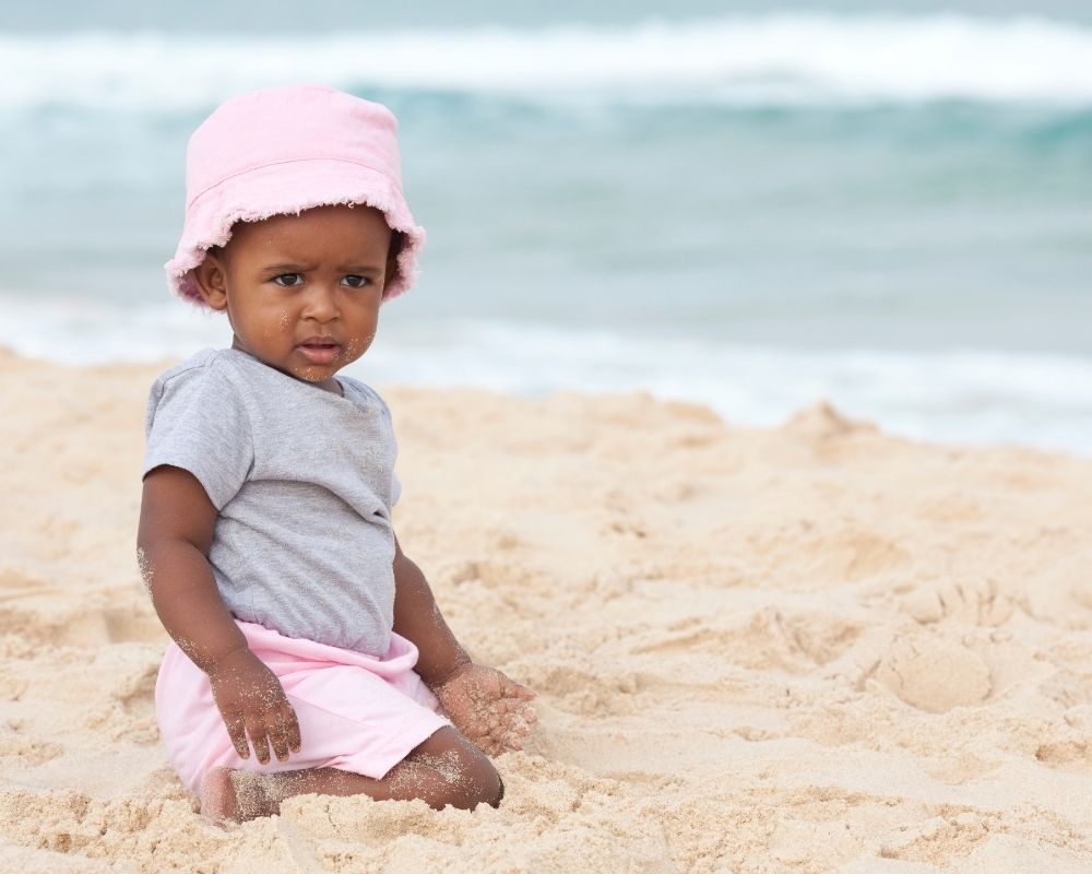 baby girl playing in the sand at the beach
