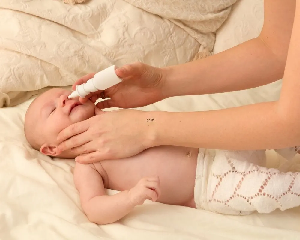 mom using a syringe bulb to clear sick baby