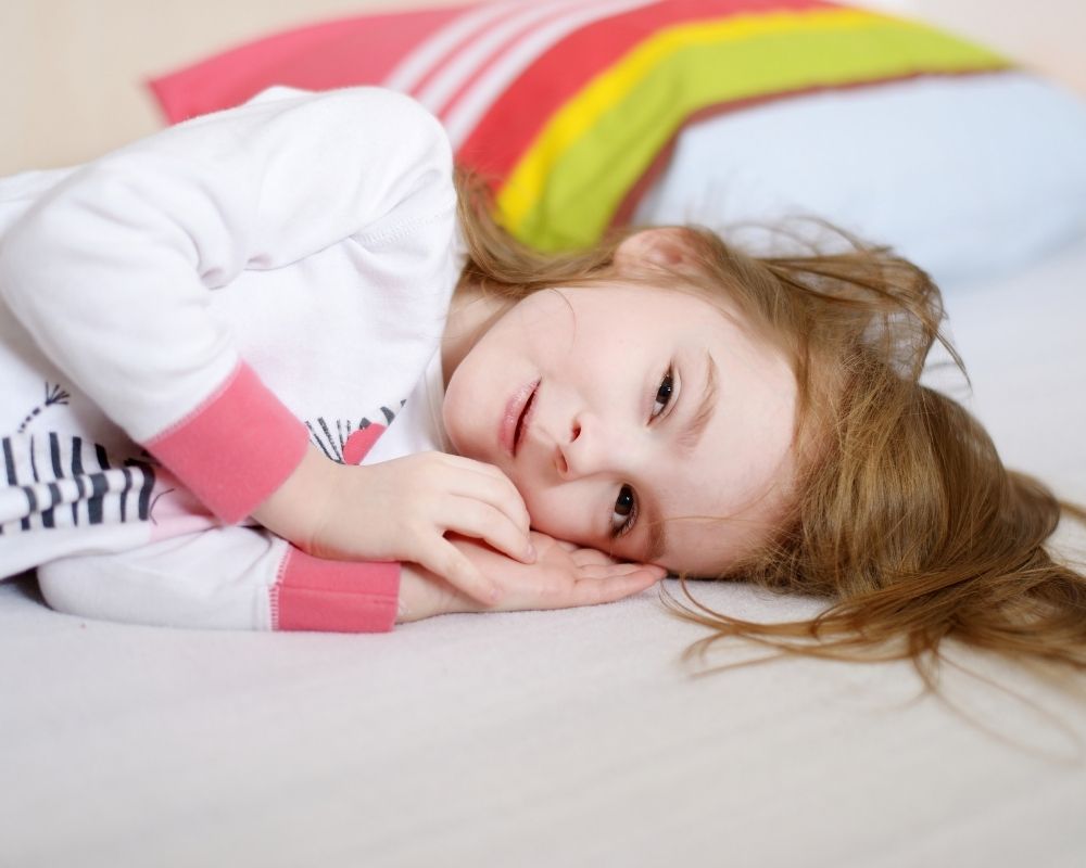 young girl laying down in bed - 4 year old sleep regression