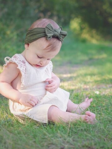 baby girl sitting in grass in summer