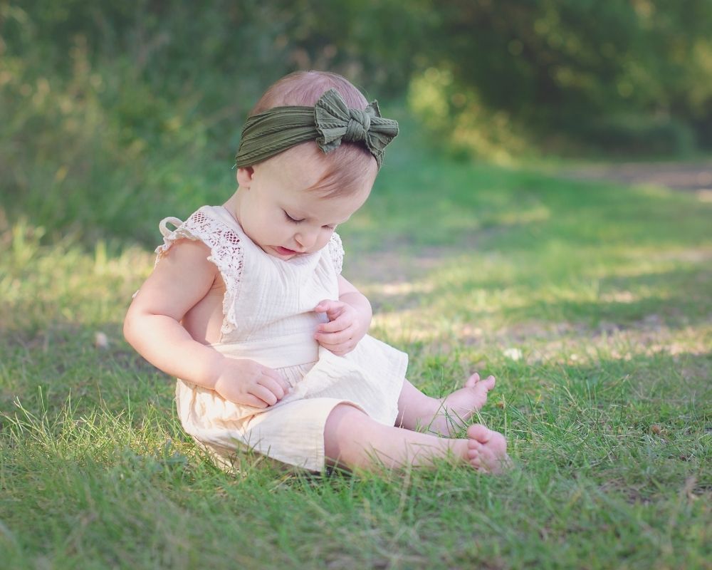 baby girl sitting in grass in summer