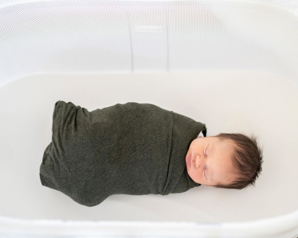 baby swaddled in a bassinet and asleep