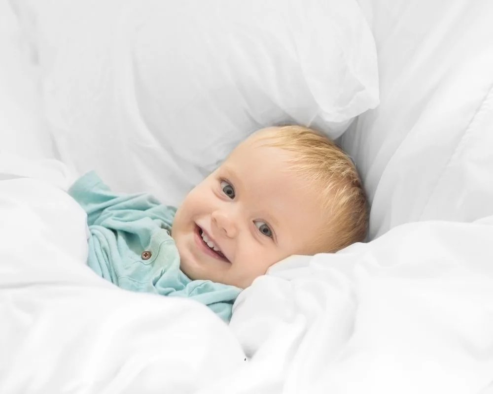 little boy smiling while laying in bed