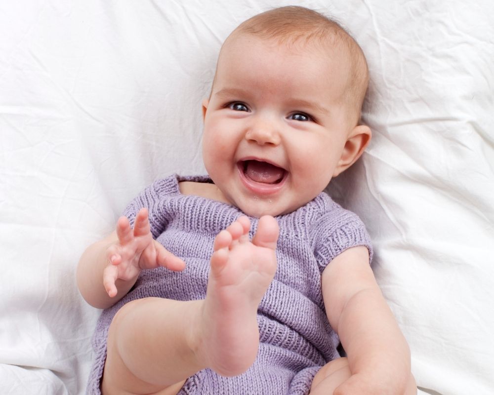 baby girl smiling and playing with feet