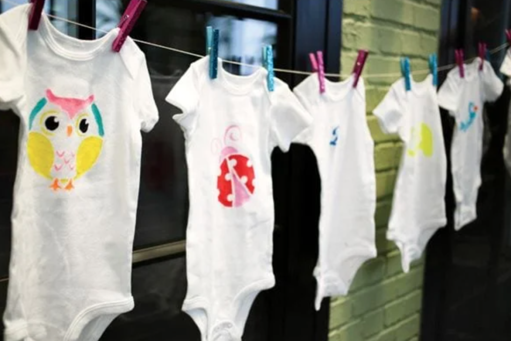 onesies decorated at baby shower and hanging from a clothesline