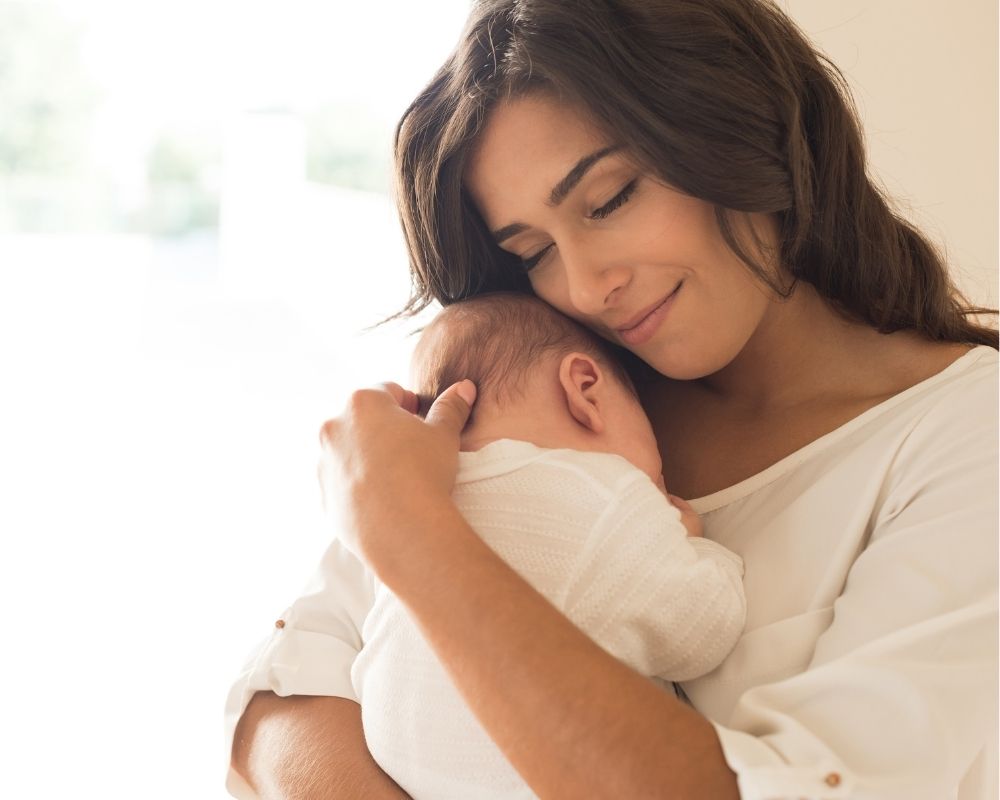 mom holding 2 month old baby in arms