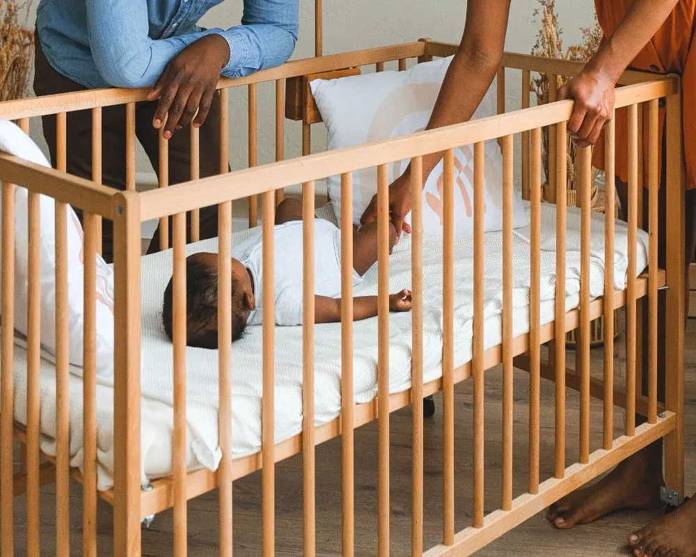 parents putting baby to sleep in crib