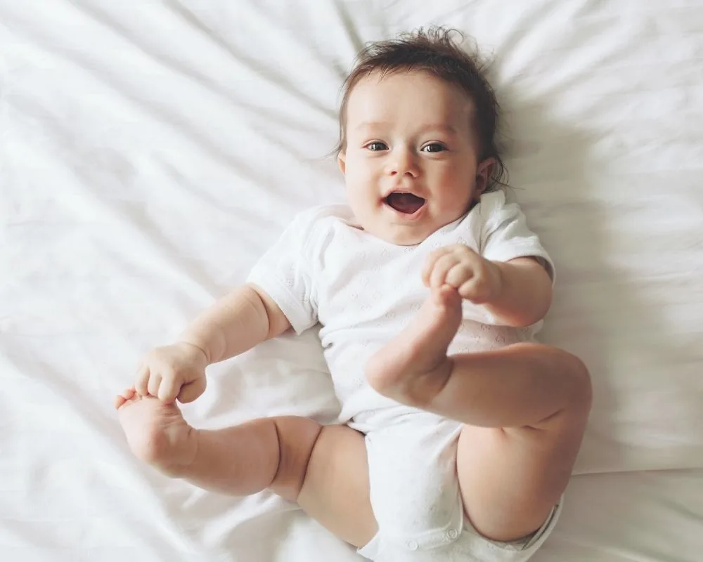 5 month old grabbing his baby toes and smiling