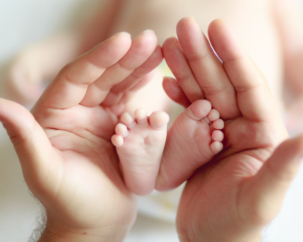 adult hands holding newborn baby's feet