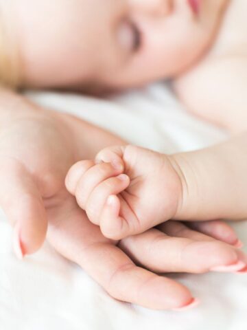 mom holding baby's hands during sleep