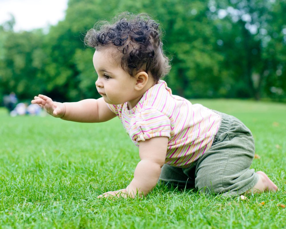 8 month old crawling on grass outside