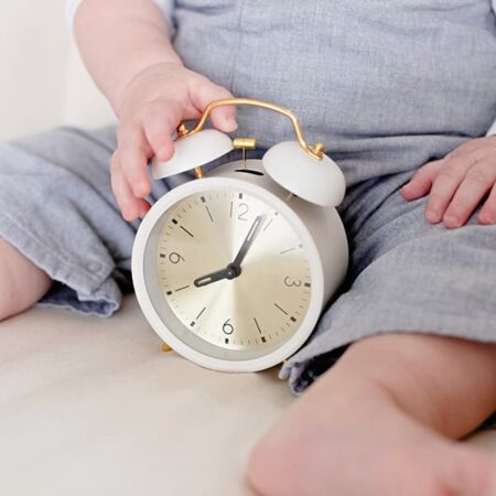 Baby Sleep Guide - baby holding clock.