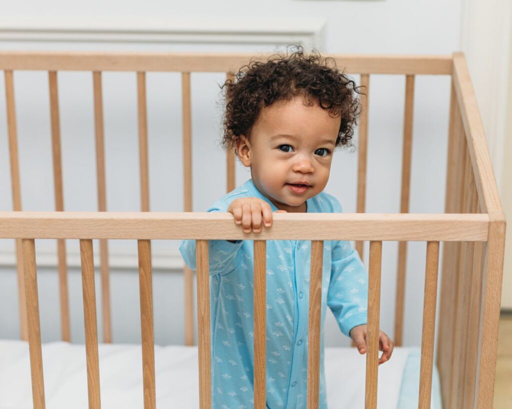 toddler boy standing in the crib