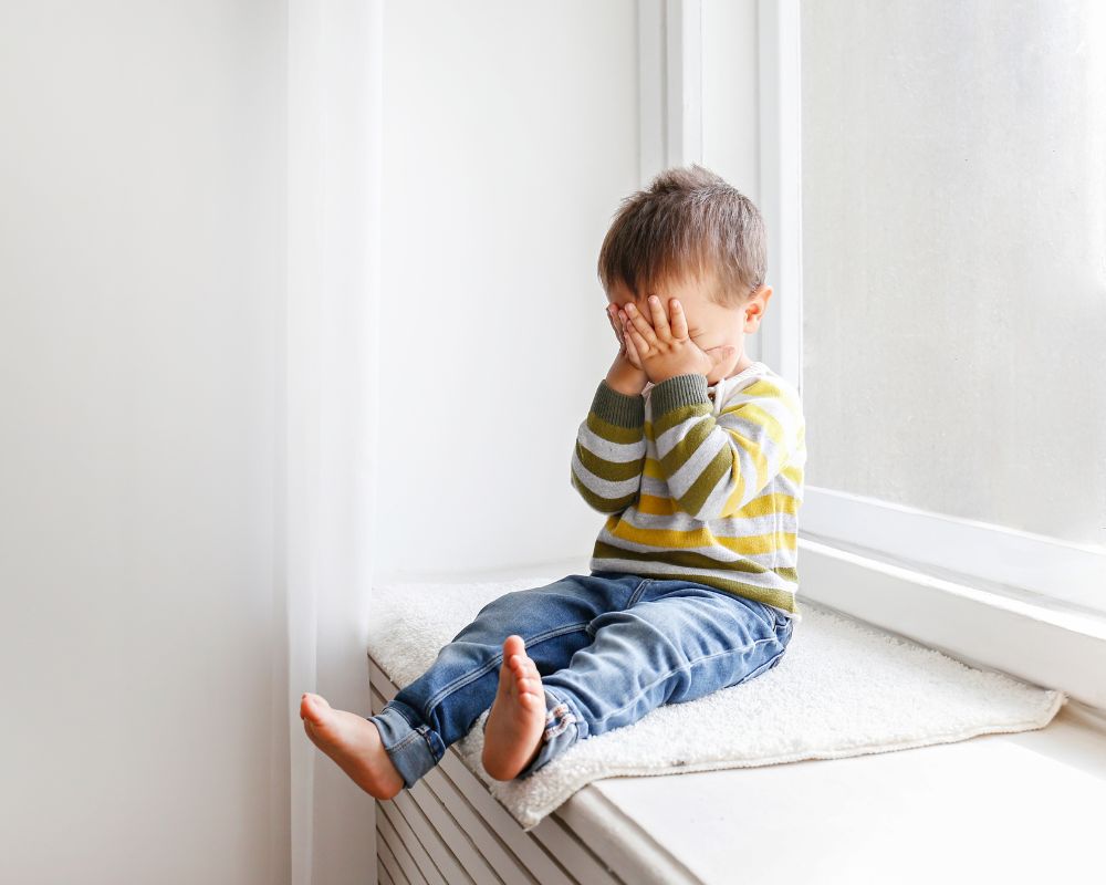 image of toddler pouting and covering his face with his hands